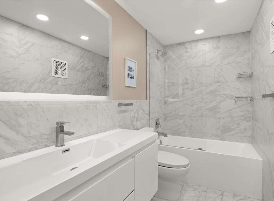 This modern bathroom features a sleek design with marble-like tiles and a minimalist aesthetic.