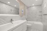This modern bathroom features a sleek design with marble-like tiles and a minimalist aesthetic.