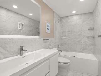 This modern bathroom features a sleek design with marble-like tiles and a minimalist aesthetic.
