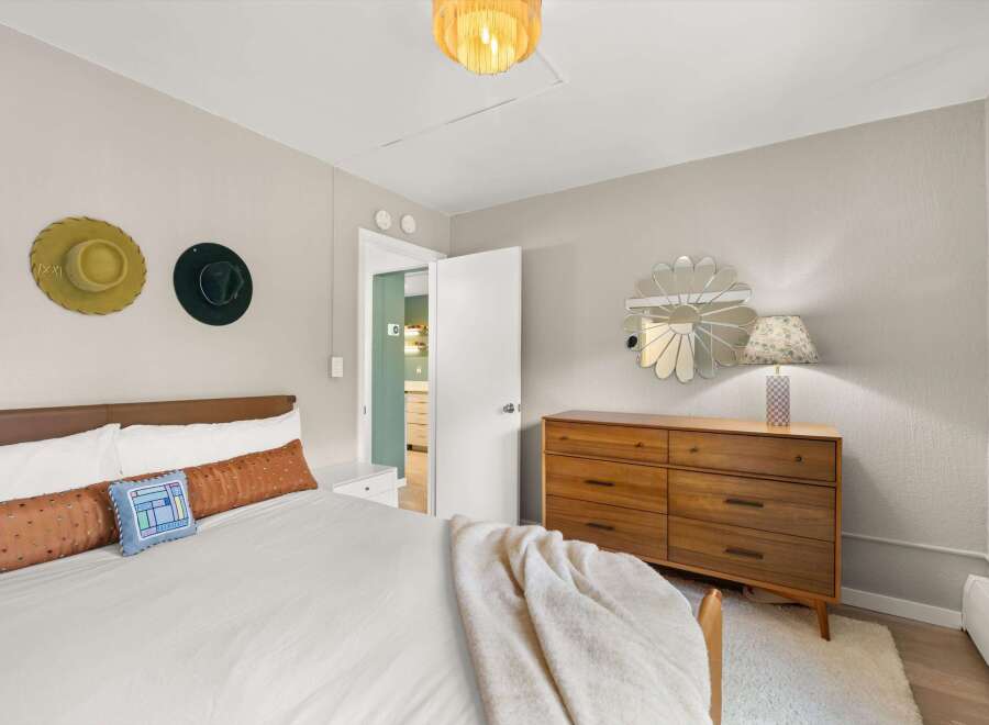 This inviting bedroom boasts a stylish design with a mid-century modern dresser and a cozy bed.