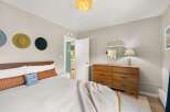 This inviting bedroom boasts a stylish design with a mid-century modern dresser and a cozy bed.