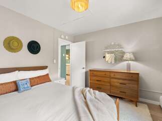 This inviting bedroom boasts a stylish design with a mid-century modern dresser and a cozy bed.