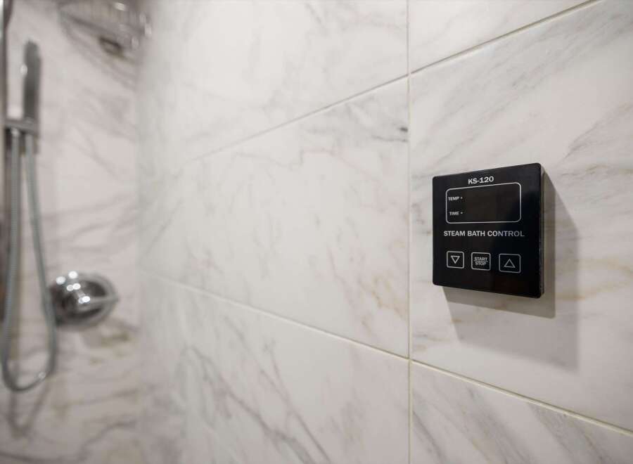 This luxurious bathroom features a modern steam bath control panel, perfect for unwinding after a long day.