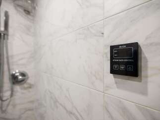 This luxurious bathroom features a modern steam bath control panel, perfect for unwinding after a long day.