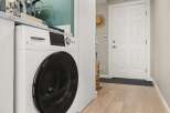 This modern laundry area features a sleek, white steam washer/dryer combo, perfect for efficient home management.