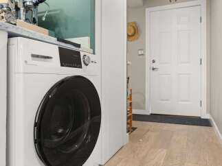 This modern laundry area features a sleek, white steam washer/dryer combo, perfect for efficient home management.