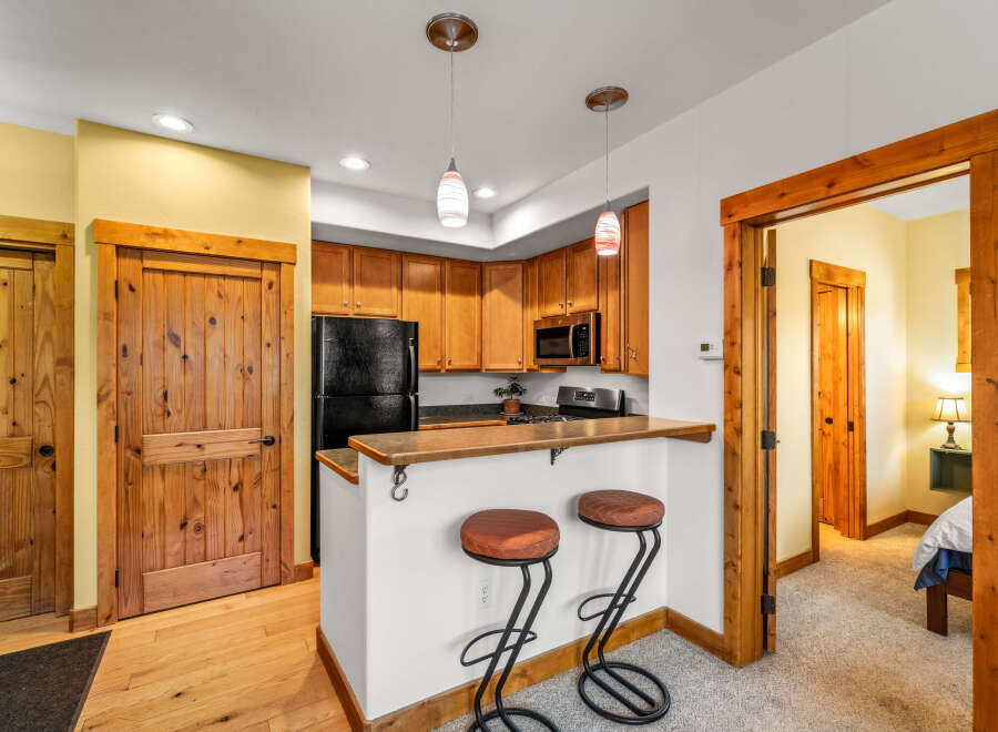 This charming kitchen features warm wooden cabinetry, a sleek black refrigerator, and a convenient breakfast bar with stylish stools.