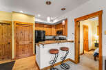 This charming kitchen features warm wooden cabinetry, a sleek black refrigerator, and a convenient breakfast bar with stylish stools.