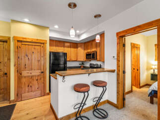 This charming kitchen features warm wooden cabinetry, a sleek black refrigerator, and a convenient breakfast bar with stylish stools.