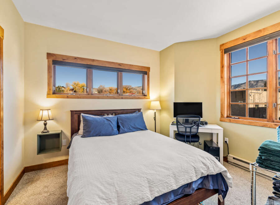 This cozy bedroom offers a comfortable retreat with its inviting ambiance and natural light.