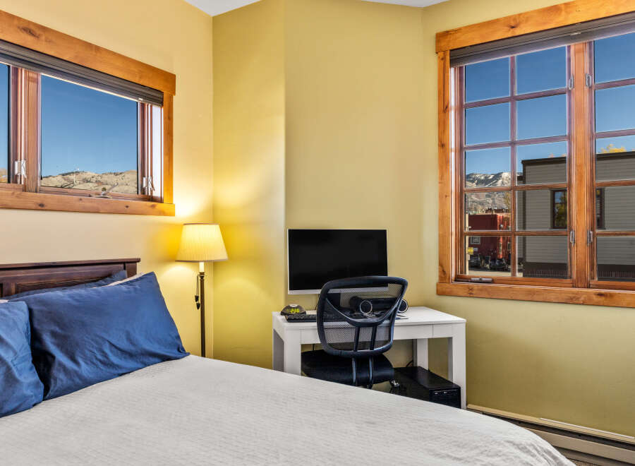This cozy bedroom features stunning mountain views framed by wooden windows.