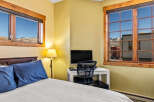 This cozy bedroom features stunning mountain views framed by wooden windows.