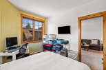 This inviting bedroom features a cozy atmosphere with a comfortable bed and a well-lit workspace.