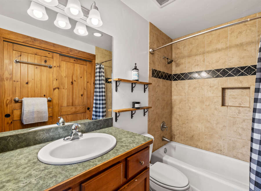 This charming bathroom features a rustic wooden vanity and a stylish checkered shower curtain.