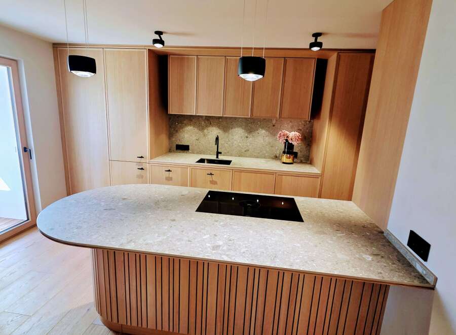 This modern kitchen boasts a sleek design with a large island featuring a cooktop and ample counter space.