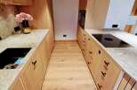 This modern kitchen showcases a sleek design with light wood cabinetry and countertops.