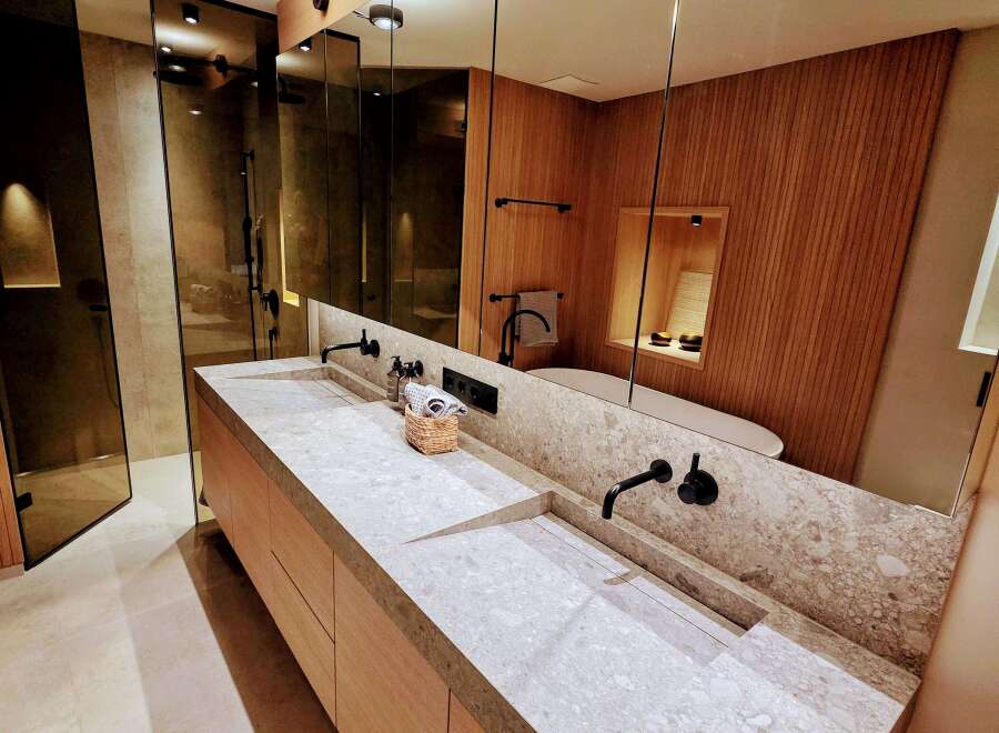 This luxurious bathroom boasts a sleek, modern design with a double vanity featuring a stunning stone countertop.
