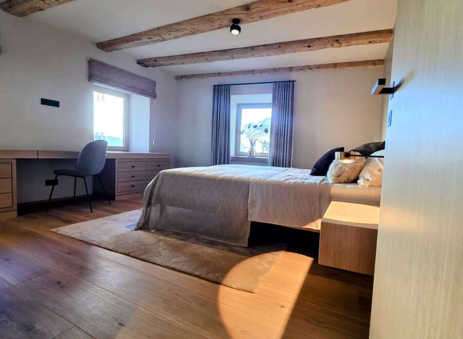 This stunning bedroom boasts a rustic charm with its exposed wooden beams and warm, inviting hardwood floors.