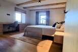 This stunning bedroom boasts a rustic charm with its exposed wooden beams and warm, inviting hardwood floors.