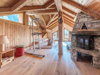 This stunning property boasts a rustic charm with its wooden interior and a cozy fireplace, perfect for a relaxing retreat.