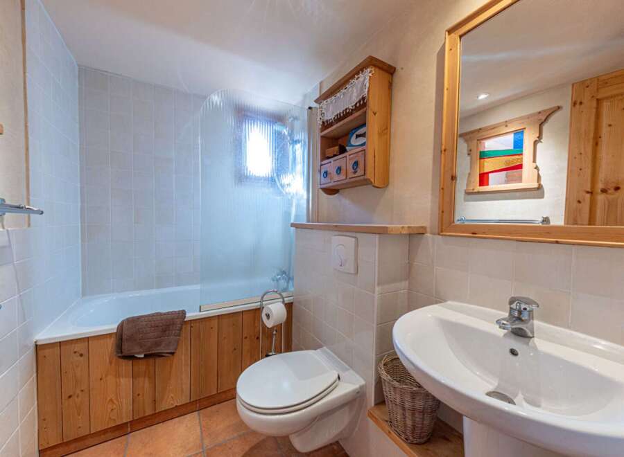 This charming bathroom features a cozy, rustic design with wooden accents and a bright, inviting atmosphere.