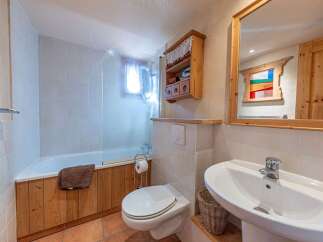 This charming bathroom features a cozy, rustic design with wooden accents and a bright, inviting atmosphere.