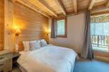 Experience the warmth of this cozy bedroom, featuring stunning wood paneling and a charming ambiance.