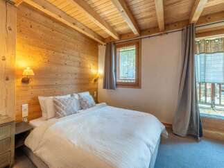 Experience the warmth of this cozy bedroom, featuring stunning wood paneling and a charming ambiance.