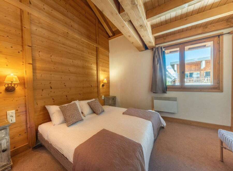 Experience the charm of this cozy bedroom, featuring warm wooden walls and a comfortable bed.