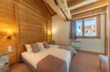 Experience the charm of this cozy bedroom, featuring warm wooden walls and a comfortable bed.