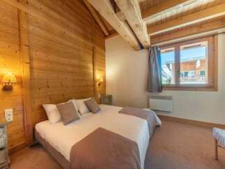Experience the charm of this cozy bedroom, featuring warm wooden walls and a comfortable bed.