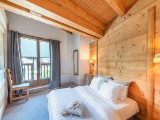 Experience the charm of this cozy bedroom featuring a rustic wooden ceiling and walls, creating a warm and inviting atmosphere.