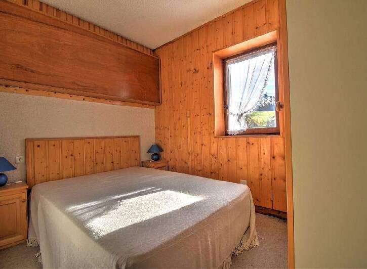 Discover the charm of this cozy bedroom featuring warm wooden paneling and a comfortable bed.