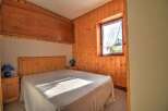 Discover the charm of this cozy bedroom featuring warm wooden paneling and a comfortable bed.