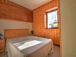 Discover the charm of this cozy bedroom featuring warm wooden paneling and a comfortable bed.