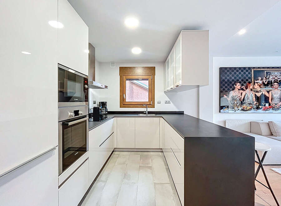 This modern kitchen boasts sleek, white cabinetry and a contrasting dark countertop, creating a stylish and functional space.