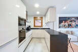 This modern kitchen boasts sleek, white cabinetry and a contrasting dark countertop, creating a stylish and functional space.