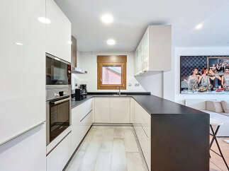 This modern kitchen boasts sleek, white cabinetry and a contrasting dark countertop, creating a stylish and functional space.