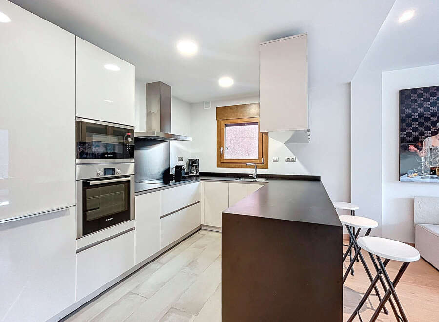 Discover modern living in this stylish kitchen! Featuring sleek, white cabinetry and stainless steel appliances, this space is perfect for culinary enthusiasts.