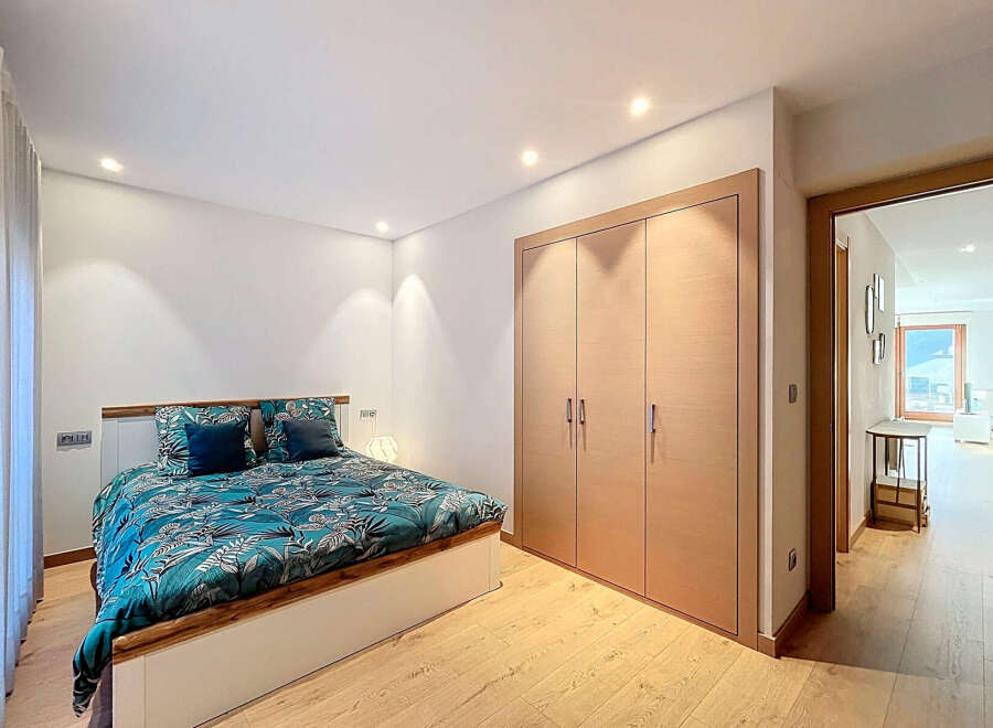 This modern bedroom boasts a stylish design with a comfortable bed featuring a vibrant teal and white patterned comforter.
