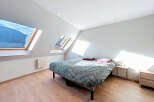 This charming bedroom boasts a unique design with its angled ceilings and skylight windows, offering stunning views and ample natural light.