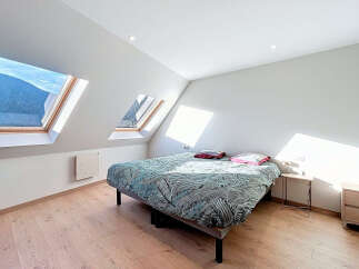 This charming bedroom boasts a unique design with its angled ceilings and skylight windows, offering stunning views and ample natural light.