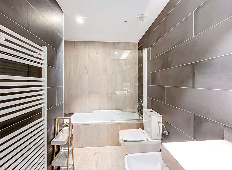 This modern bathroom features sleek, dark gray tiled walls and a bright, white ceiling, creating a sophisticated and inviting atmosphere.