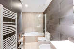 This modern bathroom features sleek, dark gray tiled walls and a bright, white ceiling, creating a sophisticated and inviting atmosphere.