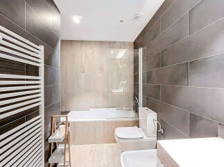 This modern bathroom features sleek, dark gray tiled walls and a bright, white ceiling, creating a sophisticated and inviting atmosphere.