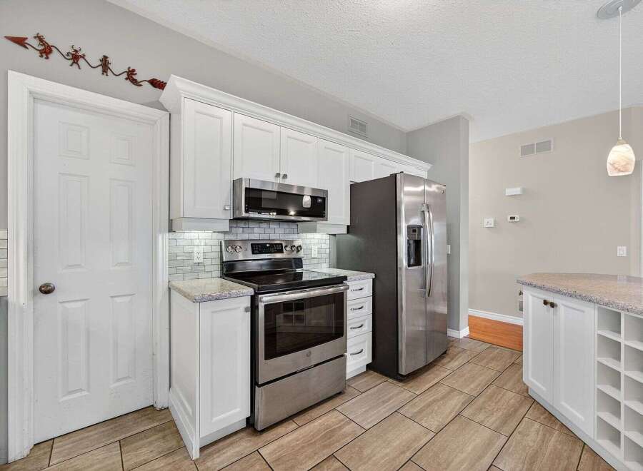 Step into this stunning kitchen, boasting modern stainless steel appliances and elegant white cabinetry.