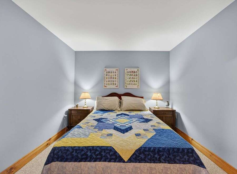 This cozy bedroom features a comfortable bed adorned with a colorful quilt, creating a warm and inviting atmosphere.