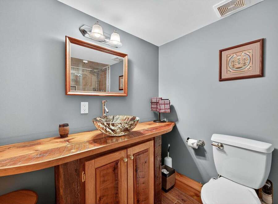Discover the charm of this unique bathroom design! Featuring a custom wooden vanity with a stylish vessel sink, this space exudes rustic elegance.