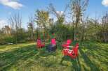 Enjoy outdoor living at its finest with this inviting property! Featuring a cozy fire pit surrounded by vibrant red Adirondack chairs, perfect for gatherings.