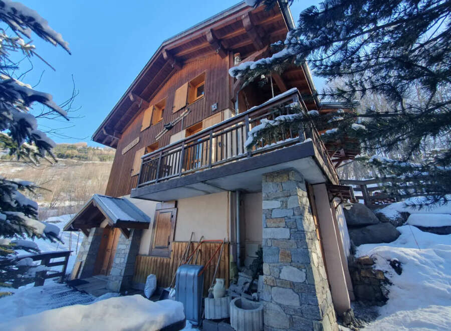 Nestled in a serene winter landscape, this charming wooden chalet offers a cozy retreat.
